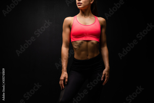 Close-up of the abdominal muscles young woman on gray background