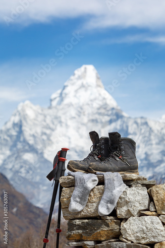 Trekking boots and socks lie on the stone in focus. Nearby are walking sticks. Mount Ama Dablam is blurry. Everest Trail Base Camp. Nepal. photo