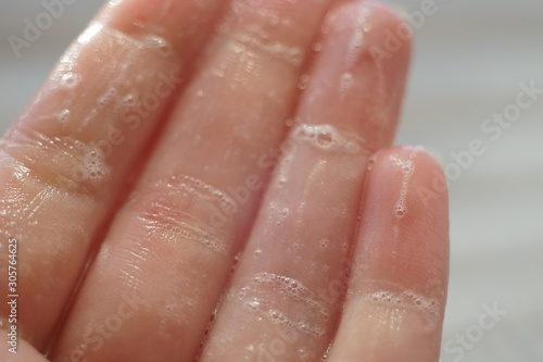 Vászonkép Wet fingers with soap foam, macro photo.