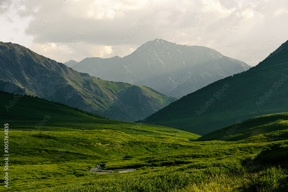 Green hills under blue cloudy sky. Mountain valley for pasture