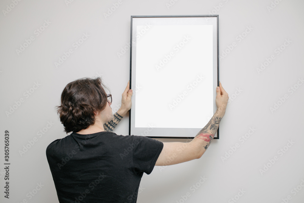 man-hanging-a-picture-or-a-poster-for-mock-up-on-a-wall-wearing-black