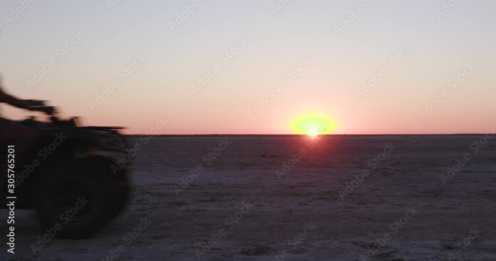 Tourists having fun driving quad bikes with the setting sun in the background on the Makgadikgadi Pans,Botswana Tourists having fun driving quad bikes with the setting sun in the background on the Makgadikgadi Pans,Botswana
