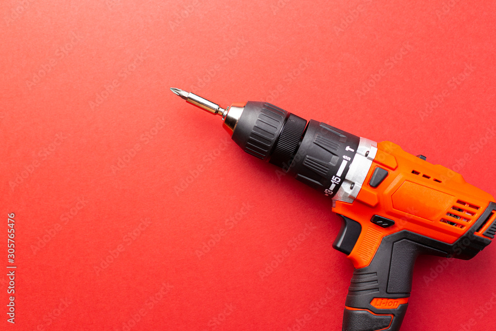 Screw driver with batteries on red background with place for text