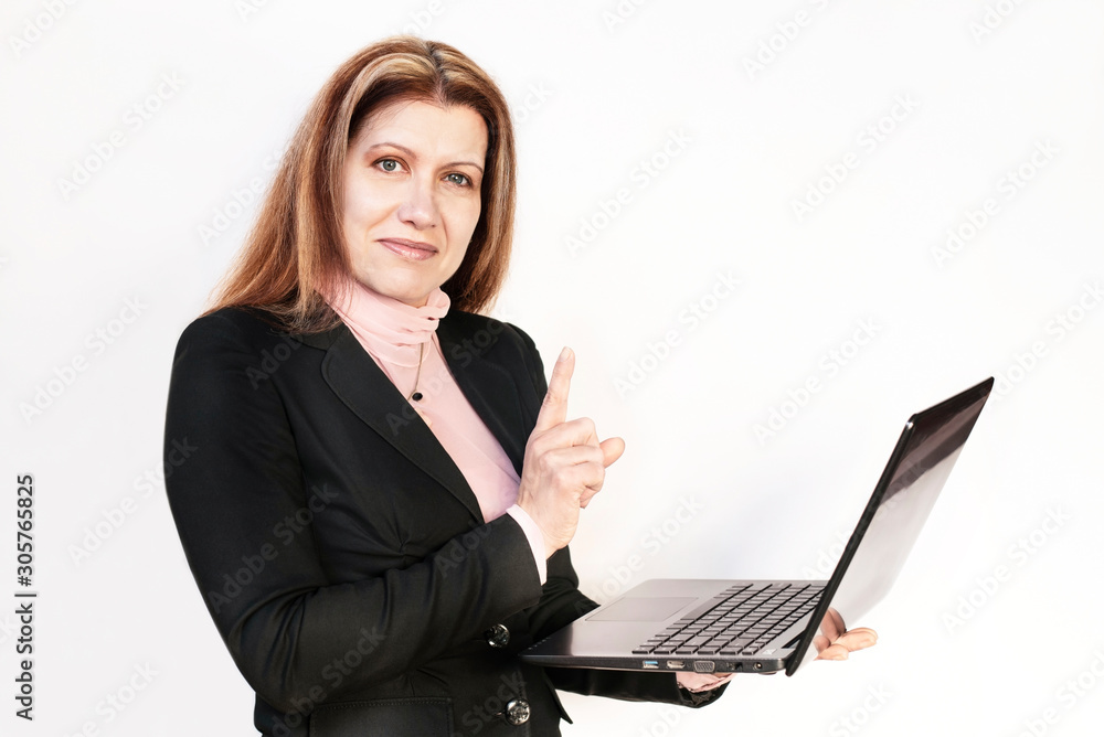 Successful woman in business suit and with a laptop in her hands smiles against a light background, she raises her finger and is delighted to have received a good letter Successful woman in business suit and with a laptop in her hands smiles against a light background, she raises her finger and is delighted to have received a good letter