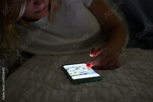 Woman scrolling through social media on smart phone at night photo