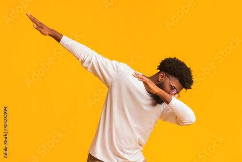 African american guy throwing dab move against orange studio background photo