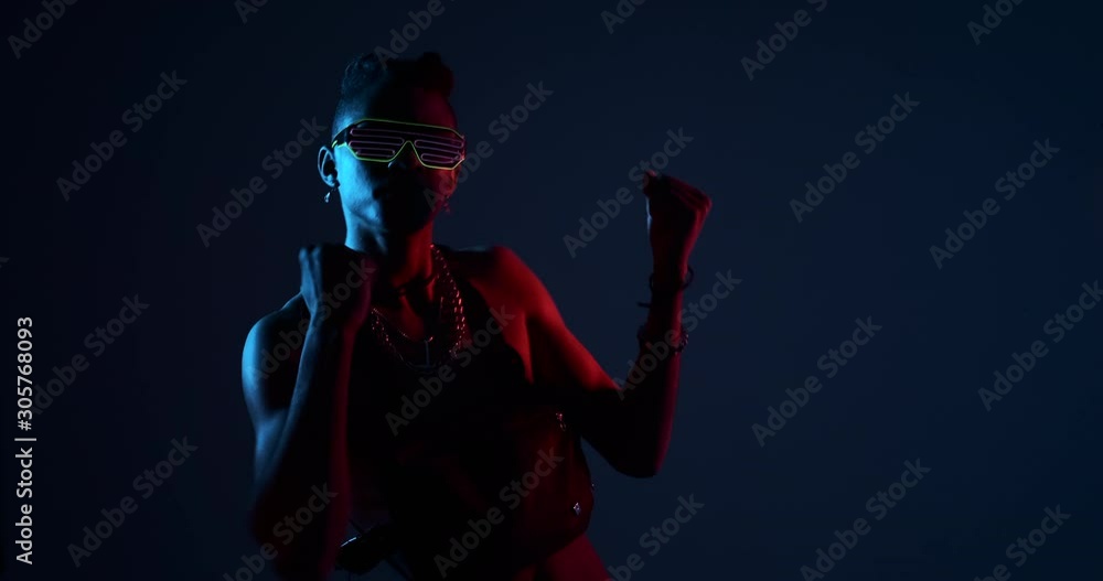 Shirtless african man dancing with bag chained necklace and glowing glasses in ultraviolet light Shirtless african man dancing with bag chained necklace and glowing glasses in ultraviolet light