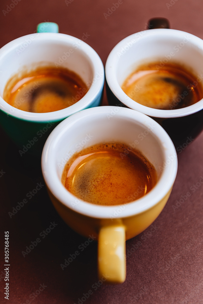 Threee colorfull cups of espresso coffee on dark background