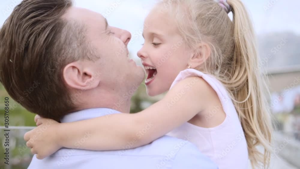 Happy family having fun together. Little fair-haired daughter playfully pretends to bite her fathers chin. Happy family having fun together. Little fair-haired daughter playfully pretends to bite her fathers chin.