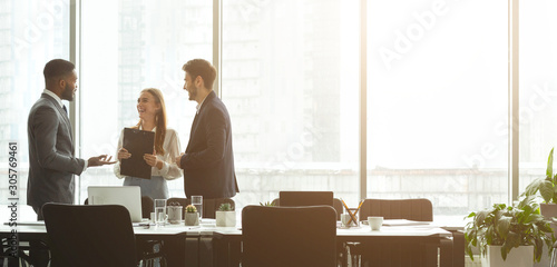 Successful businesspeople talking together in front of office windows