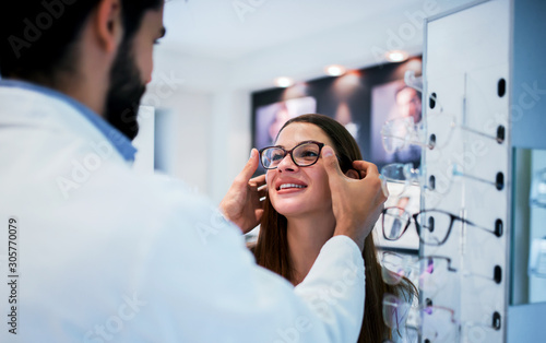 Young woman in optic store choosing a new glasses. Medical, health care concept