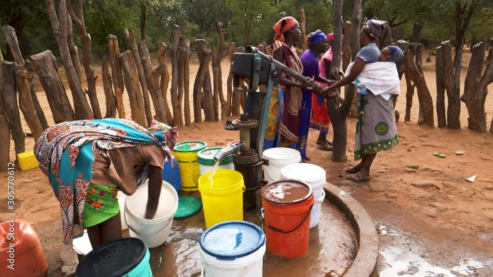 Water shortage. Six woman and a baby drawing water into plastic