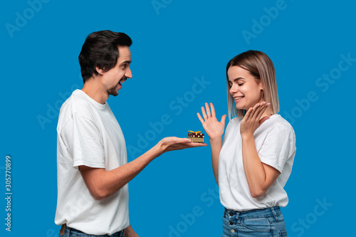Boyfriend giving present to his girlfriend isolated over blue background. Concept of love