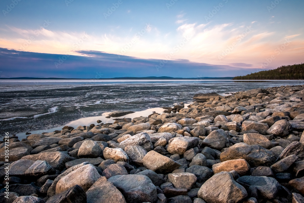 Stones on the White Sea coast at sunset. Frozen water, summer, white nights.