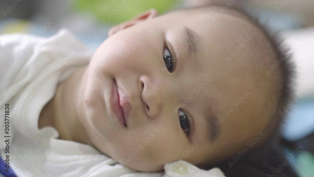 The parents rubbed the baby's head with love. The baby smiled and lay on his stomach. The parents rubbed the baby's head with love. The baby smiled and lay on his stomach.