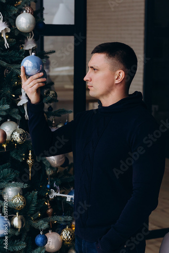 Photo session of a guy in a sweater on the eve of the new year. The guy with the Christmas toy.
