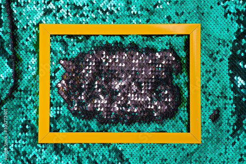 Yellow frame on a sequins green glitter wave background texture, copy space photo