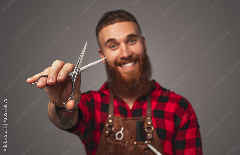 Cheerful stylish barber in bright checkered shirt with open scissors in hands Cheerful stylish barber in bright checkered shirt with open scissors in hands