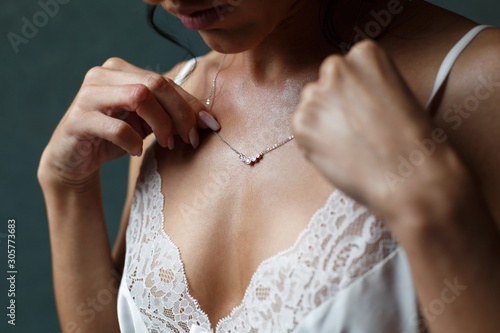 Girl in a white dress with a silver chain around her neck. The bride fixes a decoration of a jewel on the neck. Stylish fashionable diamond suspension. girl's neck pendant. pendant for women's neck.