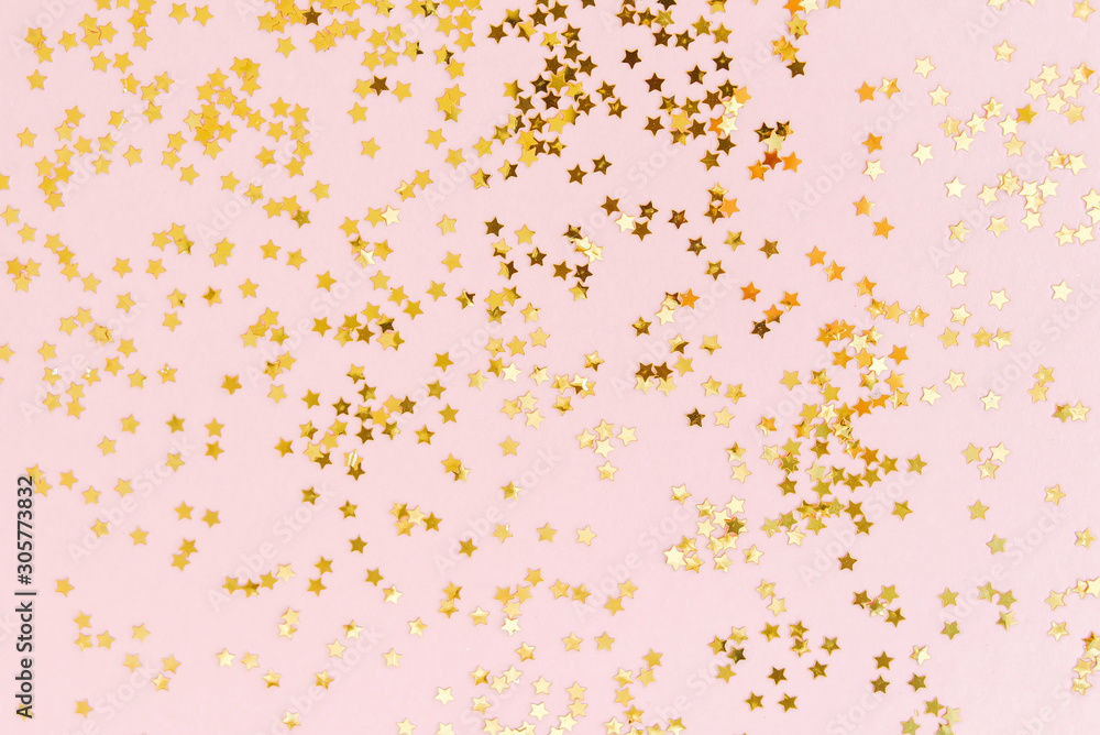 Golden star glitter confetti on pale pink background. Festive holiday background. Top view, flat lay. - obrazy, fototapety, plakaty 