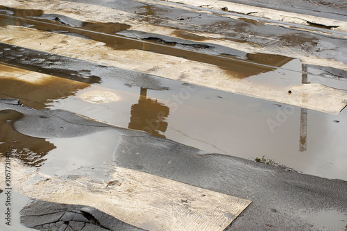 Obraz na plátně deteriorated and damaged road with puddles in the center of Milan, Italy