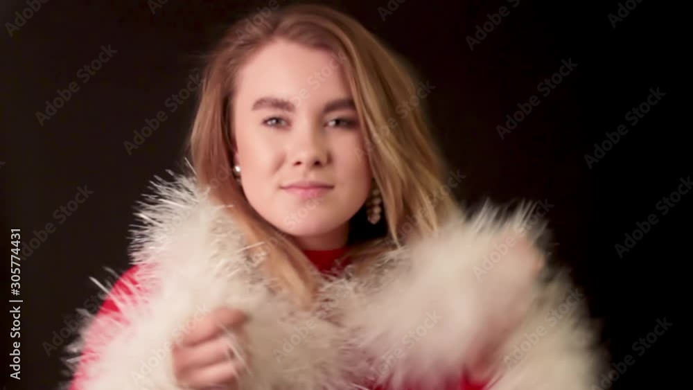Cheerful blonde girl on dark background of empty Studio dancing and gesticulating wrapped in Christmas tinsel Cheerful blonde girl on dark background of empty Studio dancing and gesticulating wrapped in Christmas tinsel
