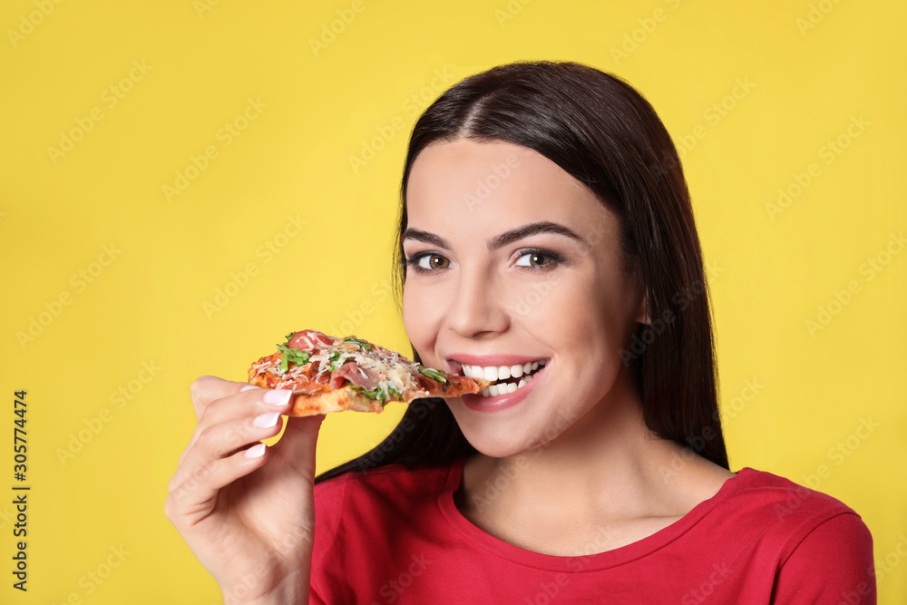 Beautiful woman eating tasty pizza on yellow background Beautiful woman eating tasty pizza on yellow background
