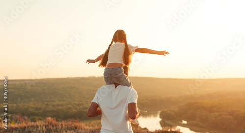 Carefree father and daughter riding on shoulders along peaceful field
