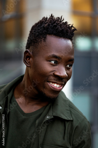 portrait of african-american man in stylish jacket on city street in the evening