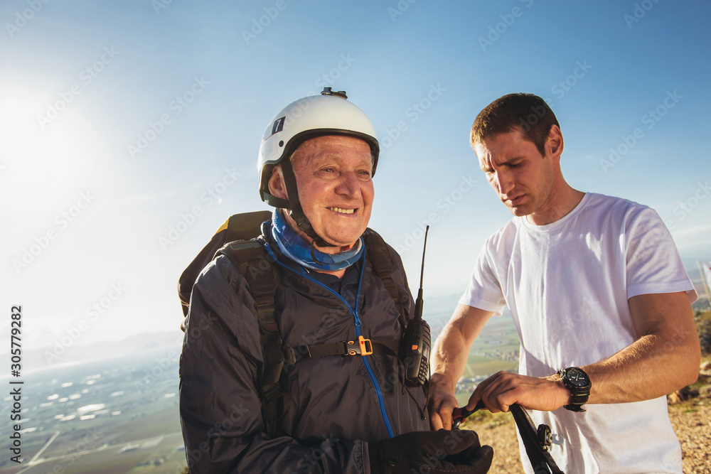 Naklejka premium Senior paraglider on the ground prepairs to fly.