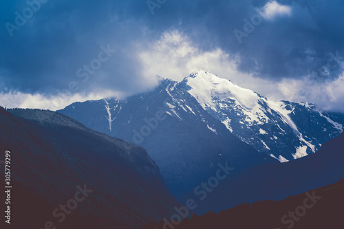 Mountain range under cloudy sky. Snowy peaks of mountains rocks