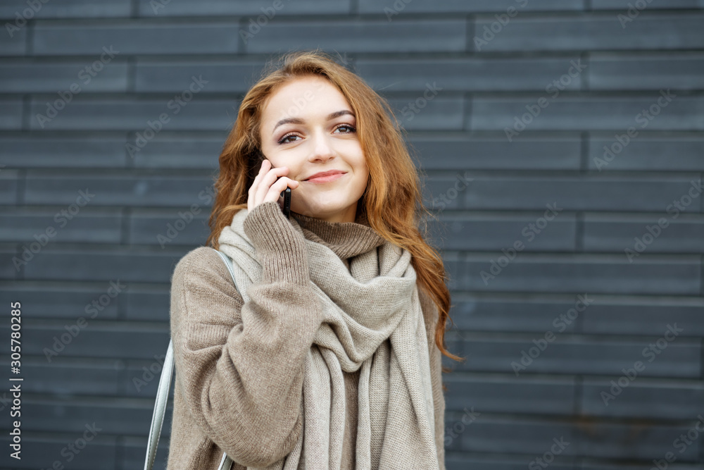 A young woman is talking on the phone and smiling on the street. The concept of communication, work, lifestyle and youth. A young woman is talking on the phone and smiling on the street. The concept of communication, work, lifestyle and youth.
