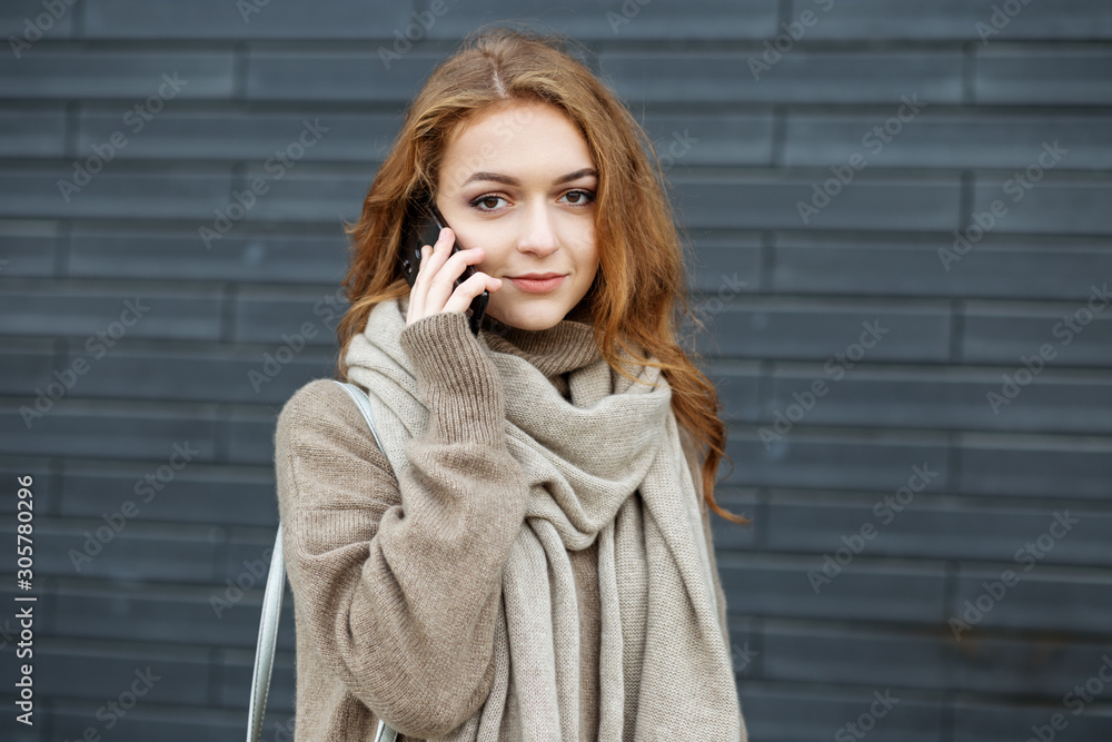 A young woman is talking on the phone in the street. The concept of communication, work, lifestyle and youth A young woman is talking on the phone in the street. The concept of communication, work, lifestyle and youth