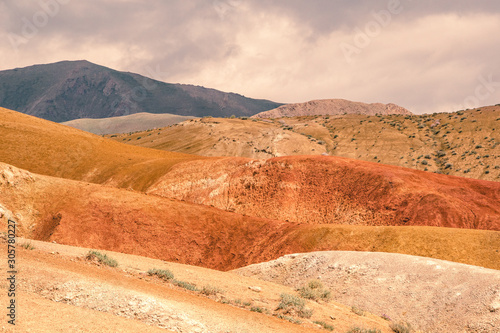 Colored hills in mountain valley. Dry sandy red hills on hot summer day. Drought, climate change. Soil erosion in ravines