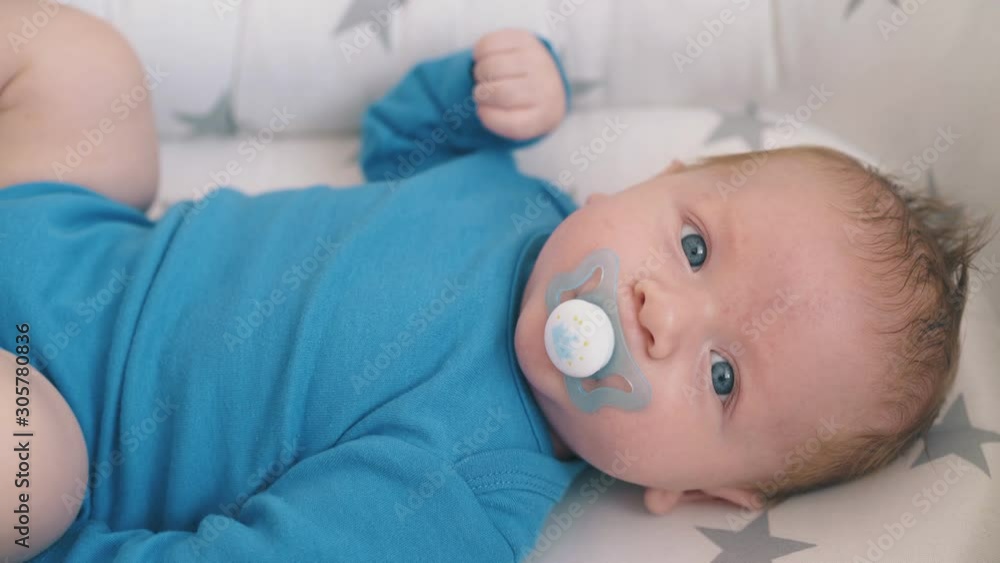 lovely blue eyed baby sucks butterfly shaped dummy in cozy cocoon with star patterns extreme closeup lovely blue eyed baby sucks butterfly shaped dummy in cozy cocoon with star patterns extreme closeup