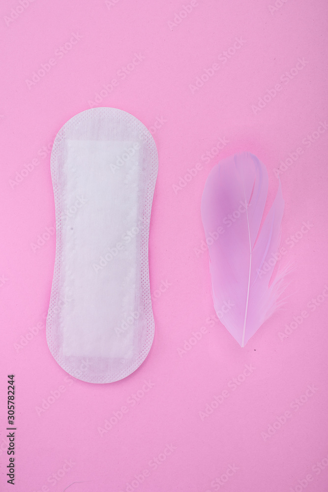 Menstrual pad with feathers on color background Menstrual pad with feathers on color background