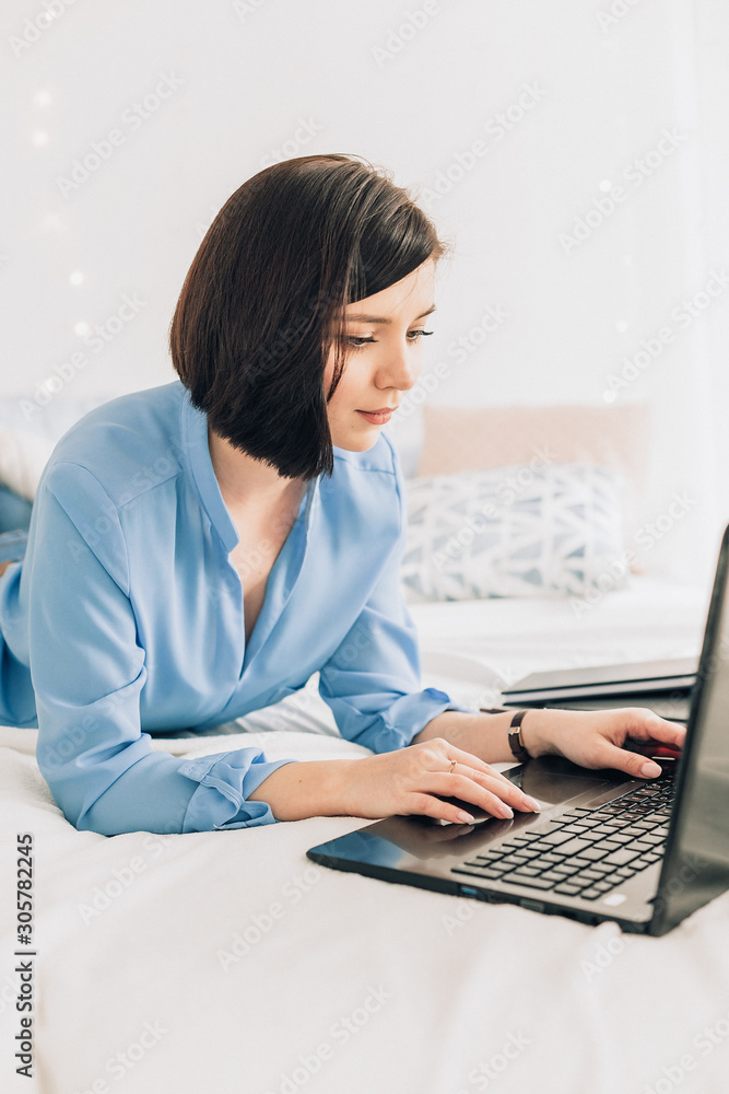 Businesswoman working on her laptop in the white bed. Work at home. Freelancer Businesswoman working on her laptop in the white bed. Work at home. Freelancer