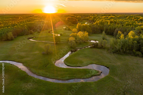 Forest in summer colors. Green deciduous trees and winding blue river in sunset. Mulgi meadow, Estonia, Europe photo