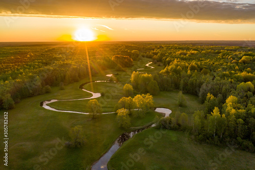 Forest in summer colors. Green deciduous trees and winding blue river in sunset. Mulgi meadow, Estonia, Europe photo