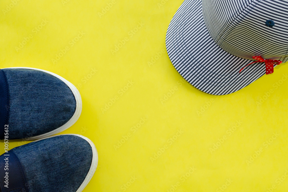 Top view and close up: Denim or jean cloth slip on shoes, sneaker, baseball cap on yellow background Top view and close up: Denim or jean cloth slip on shoes, sneaker, baseball cap on yellow background