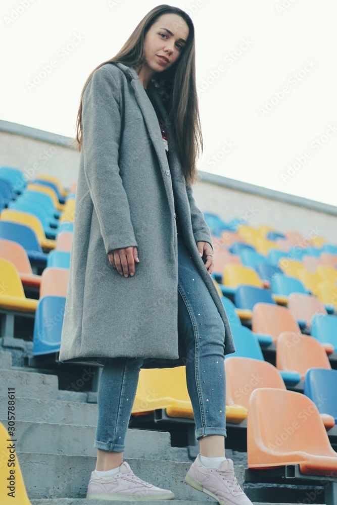 Sensual portrait of beautiful young girl walking in the old abandoned stadium on cold autumn day