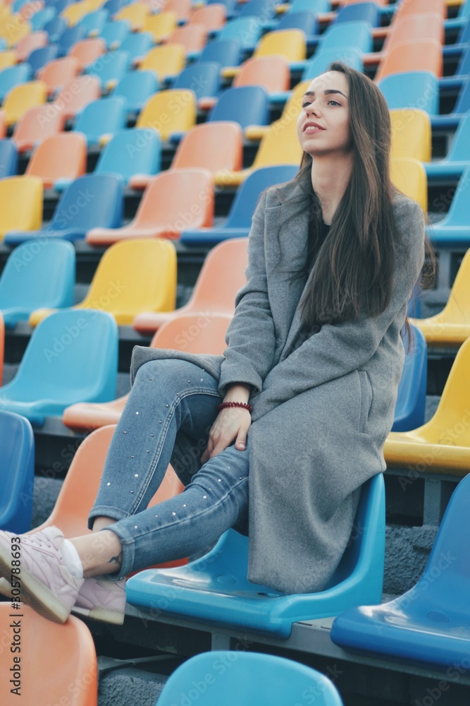 Sensual portrait of beautiful young girl walking in the old abandoned stadium on cold autumn day