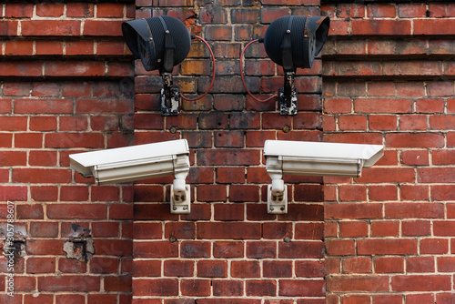 Two surveillance cameras on a red brick wall, with infrared spotlights
