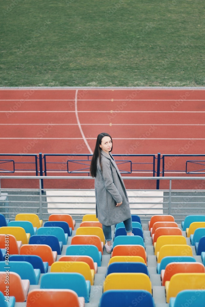 Sensual portrait of beautiful young girl walking in the old abandoned stadium on cold autumn day