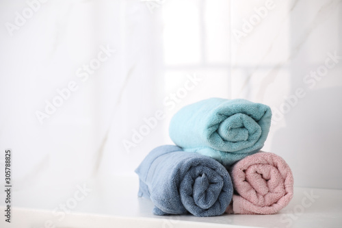Rolled fresh towels on countertop in bathroom. Space for text