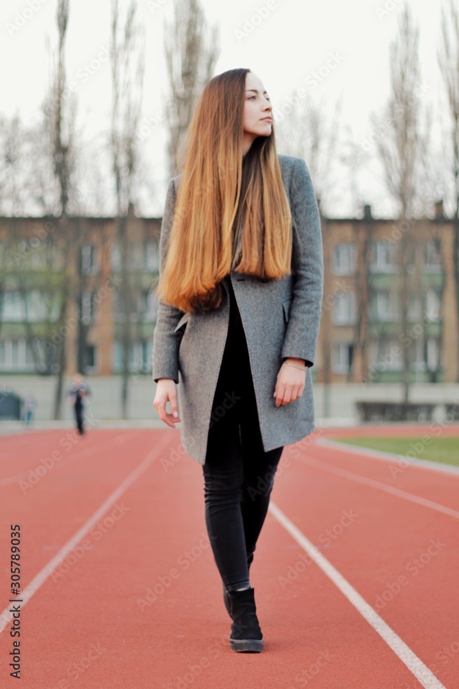 Sensual portrait of beautiful young girl walking in the old abandoned stadium on cold autumn day