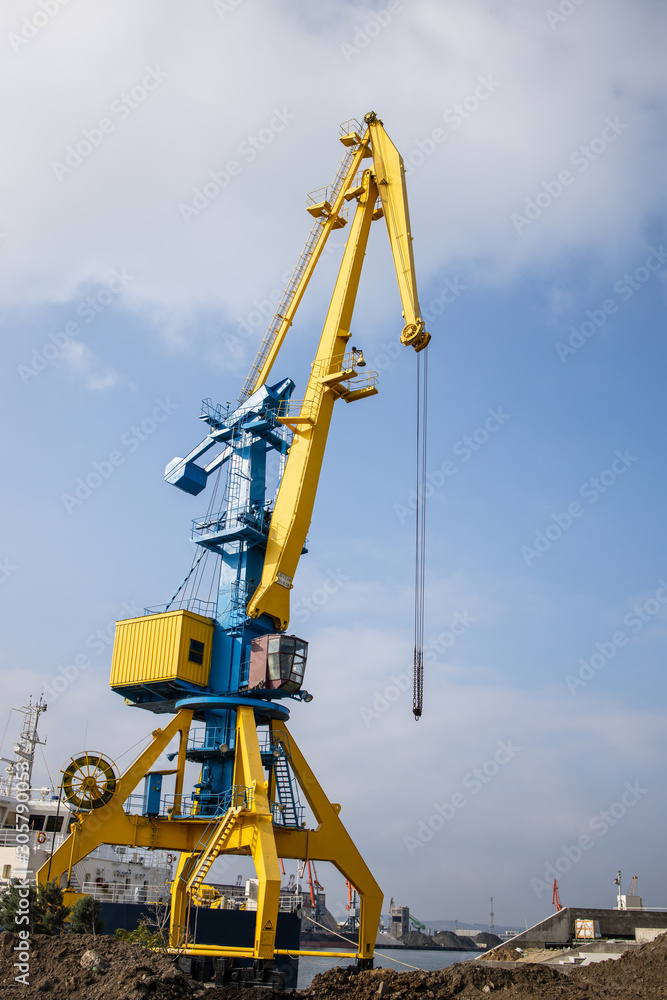 Working cranes in Bourgas - Bulgaria port in sunny weather. Industrial crane for unloading and loading in sea. Vertical image. Working cranes in Bourgas - Bulgaria port in sunny weather. Industrial crane for unloading and loading in sea. Vertical image.
