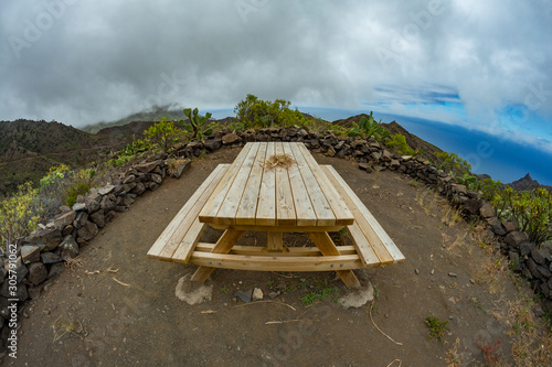 Parque Natural Majona. Wooden table and benches, place for relaxing with beautiful views of the north-eastern part of La Gomera island. Fisheye lens shot. Canary Islands, Spain