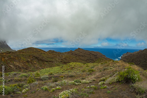 Narrow rural road in the mountains of Parque Natural Majona. Low wet clouds hanging over the green slopes. View of the north-eastern part of La Gomera island. Canary Islands, Spain © Yury