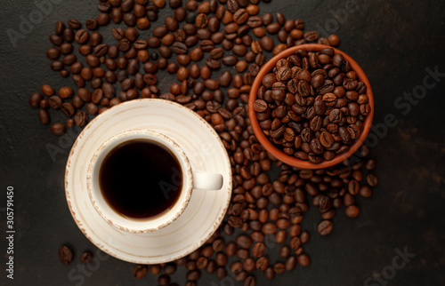Cup of coffee and different beans on a stone background.